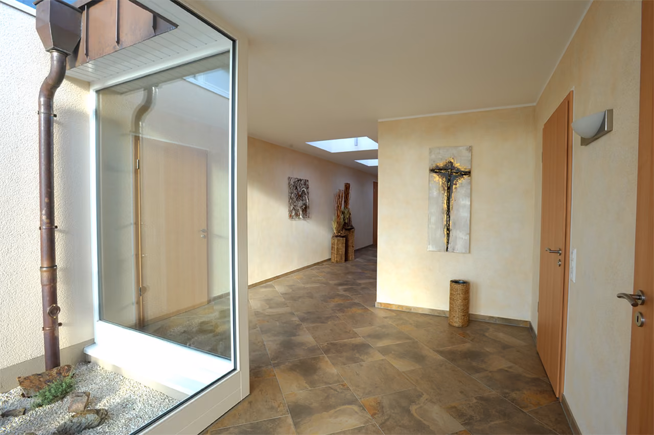 Flur im Bestattungshaus Rödinghausen mit Glasatrium und Kreuz an der Wand